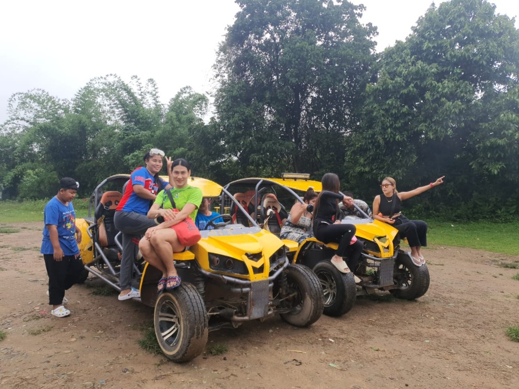 Travelers posing on yellow off-road buggies in Vang Vieng