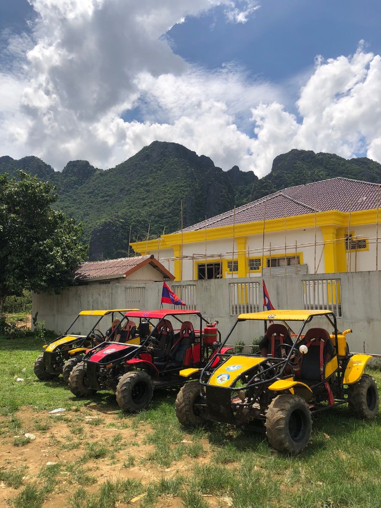 Three yellow and red buggies parked with mountain backdrop